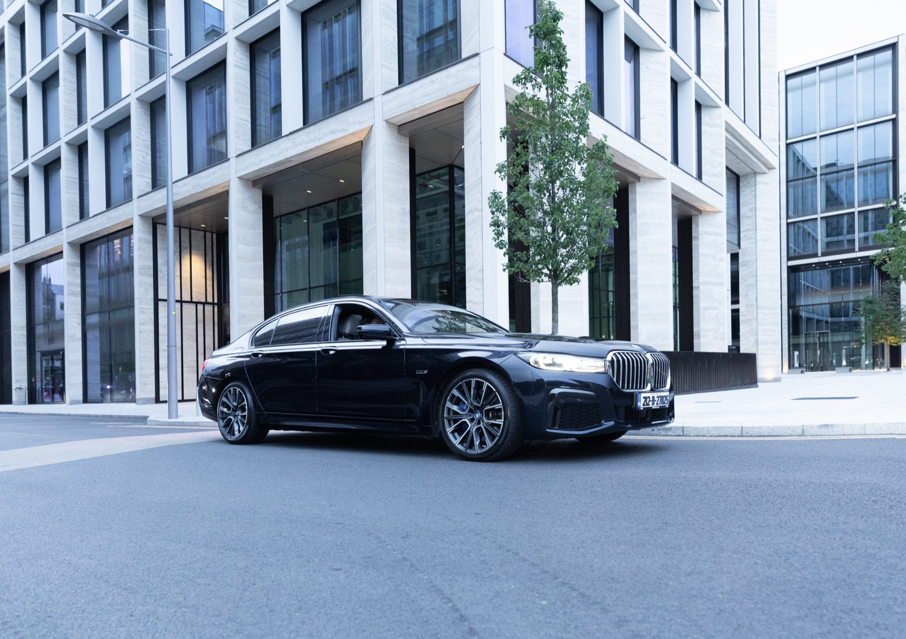Black BMW 7 Series waiting outside a modern Dublin office building